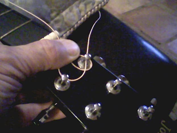 Do one turn around the peg, then insert string through hole.