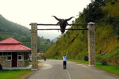A tourist raising hands in front of the entrance of Obudu Cattle Ranch in Calabar, Nigeria