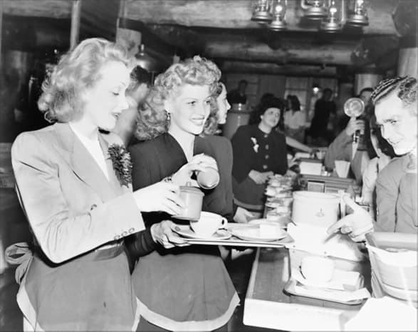 Marlene Dietrich and Rita Hayworth serve food to soldiers at the Hollywood Canteen Los Angeles California (17 November 1942).