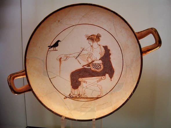 Apollo Cup, 480-470 BCE. White-ground pottery. The god has his turtleshell lyre and is pouring an offering to himself. A raven or crow -- both associated with him because of their intelligence -- looks on.