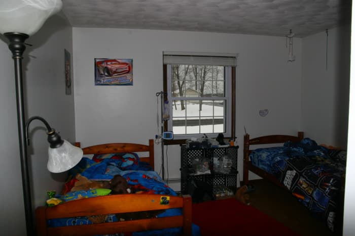 The boys' bedroom before the transformation: drab, white walls and uncoordinated bedding.