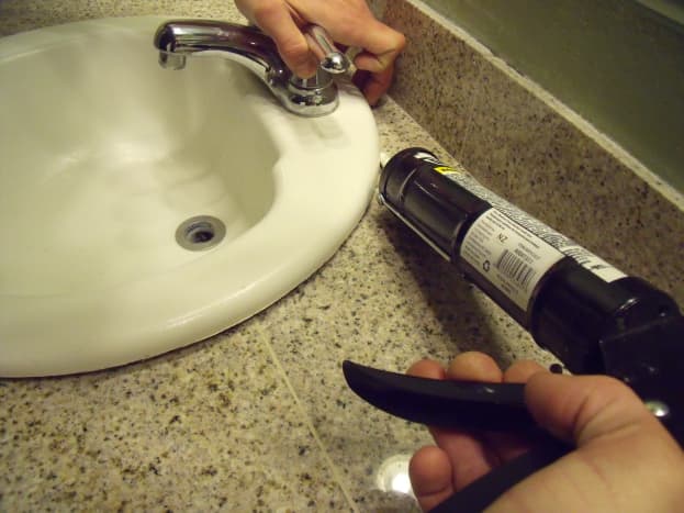 Use a caulking gun to apply silicone caulk around the sink.