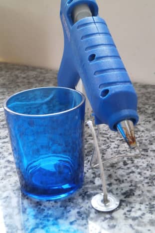 Use a hot glue gun to attach a pre-made candle wick to the bottom of the glass container.