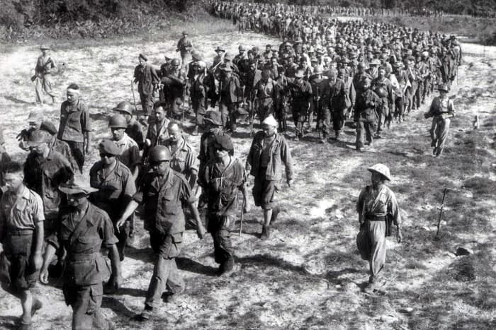 Captured French soldiers from the battle of Dien Bien Phu, escorted by Vietnamese troops, walk to a prisoner-of-war camp