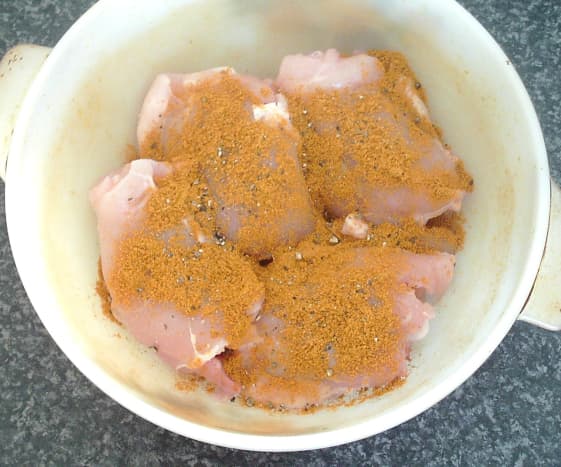 Curry powder and seasoning is scattered over chicken thighs
