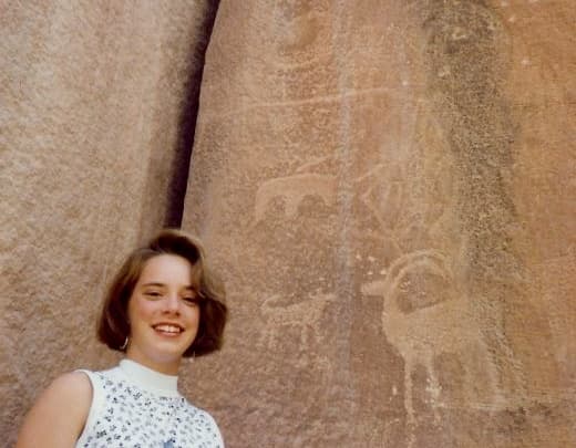 Photo of my niece standing in front of some petroglyphs 