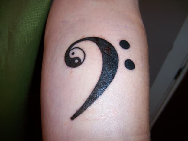 An F-clef tattoo with a yin yang inside it.