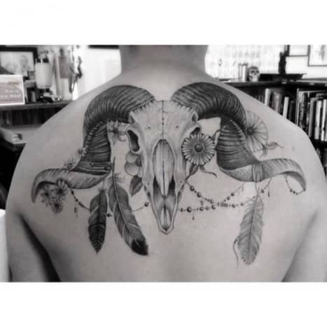 Ram skull Aries tattoo with feathers and flowers