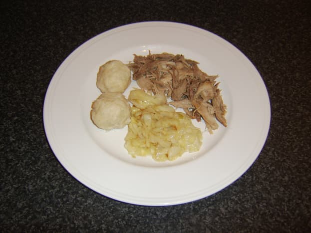 Pulled pork, potato dumplings and cabbage are arranged on serving plate