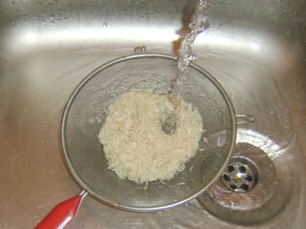 Rice is washed under running cold water
