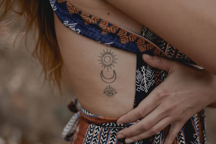 Sun, moon, and eye tattoo on side ribs