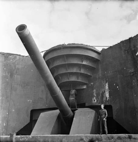 A British soldier poses next to the recently captured German 380 mm gun Todt Battery at Cap Gris Nez soon after D-Day landings.