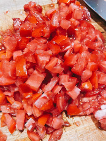 On a cutting board, dice the tomatoes. I prefer to dice them into chunks. 
