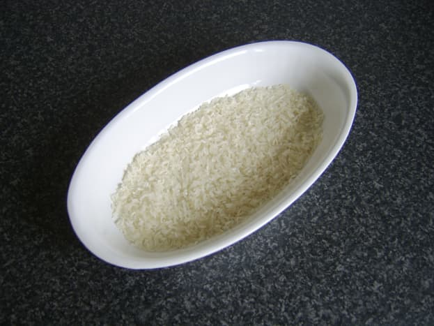 Rice is spread evenly over the base of an ovenproof dish
