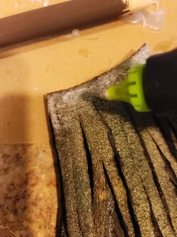 Spread two thin lines of hot glue on the top edge, back of your bristles, to secure them to your handle.