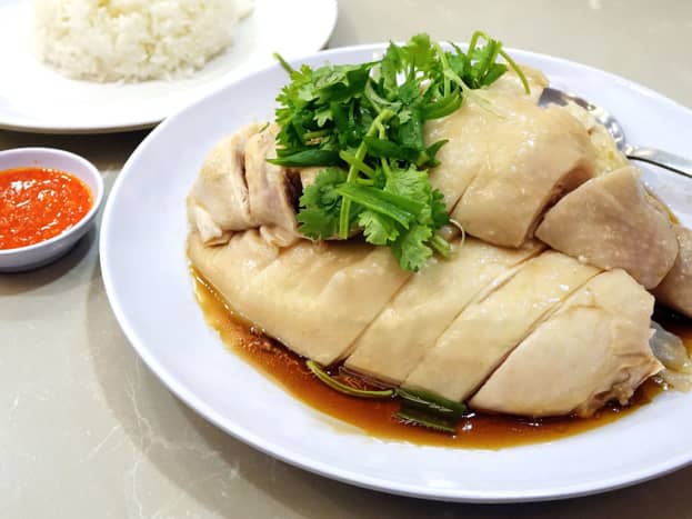 Singaporean-style chicken rice is served with roasted or steamed chicken. The rice itself is lightly flavored. Accompanying chili sauce typically includes garlic too.