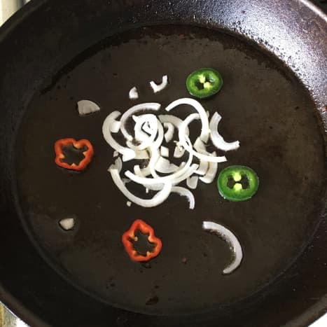 Chilli slices and onion are added to frying pan