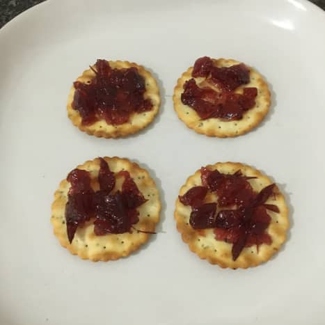 Cranberry sauce is spread on crackers