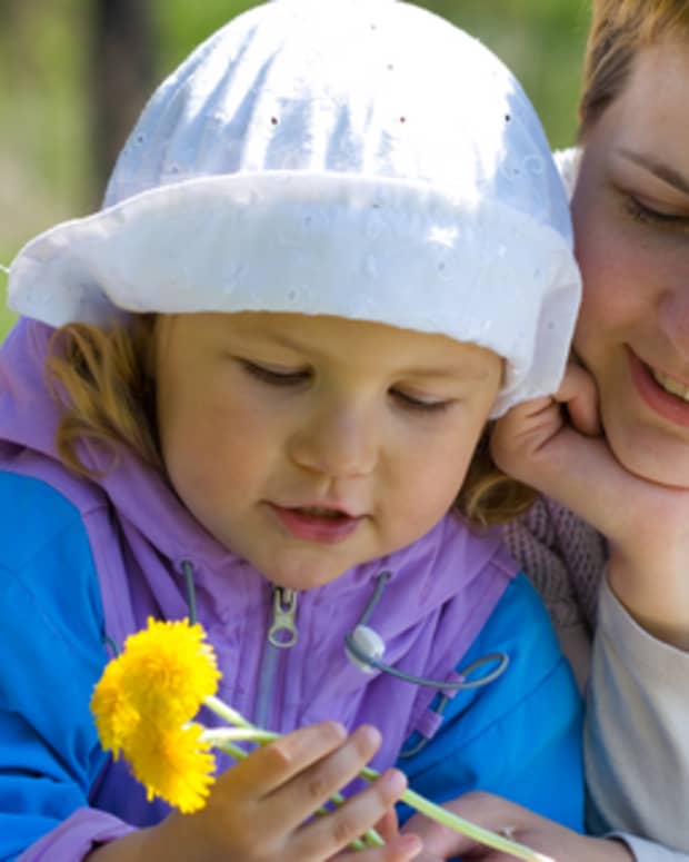 Mother and preschool-aged daughter holding dandelions