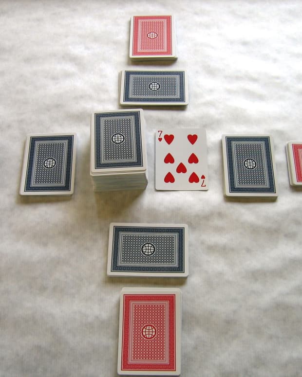 The table is set for play. Front hands in red, back hands in blue. The pick up and discard piles are in the center. Players may only look at their front hand cards first, and may not look at the back hand until they have played through the front hand