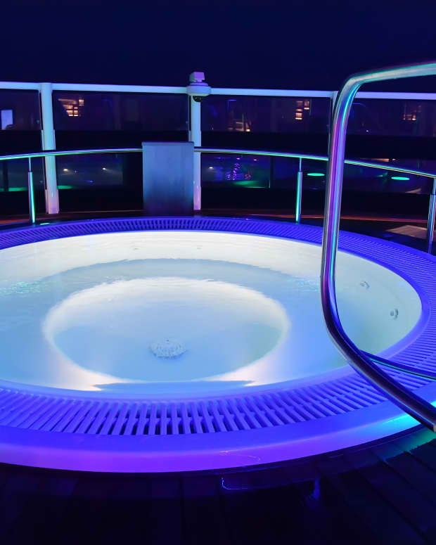 a hot tub on a cruise ship lit up with purple and blue lights at night.