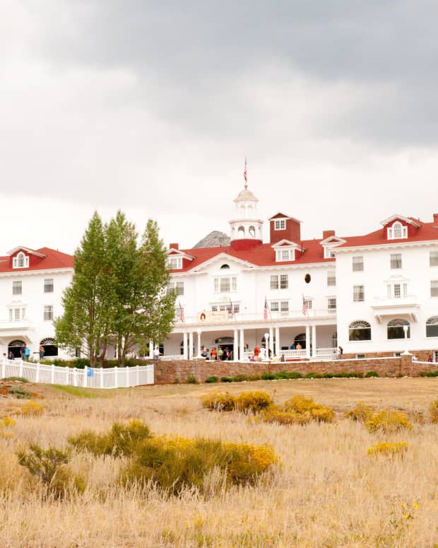 The Stanley Hotel with its white walls and red roofs against a stormy sky.