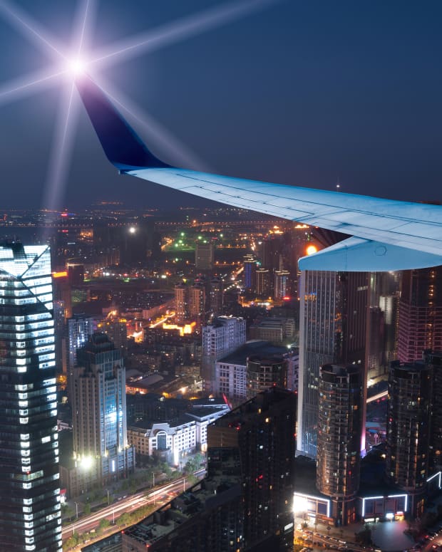 The wing of a plane passing over a city at night