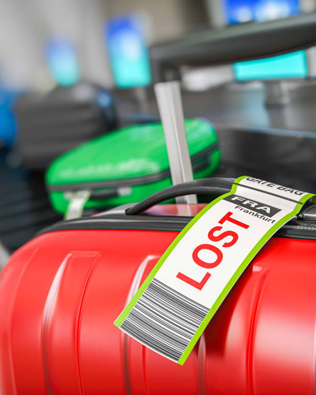 Red suitcase with a lost sticker on the luggage conveyor belt