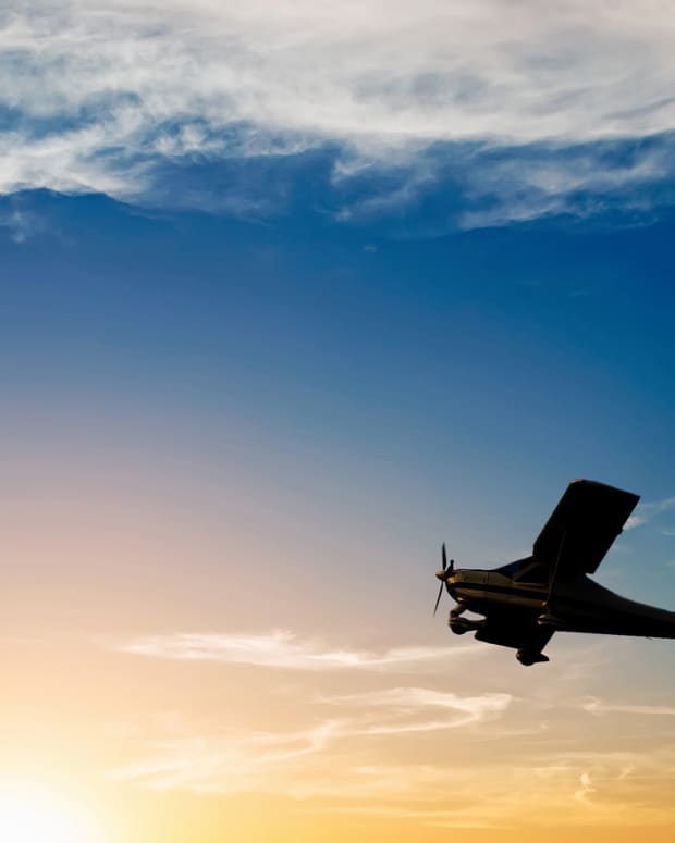 Silhouette of a single engine airplane flying at sunset