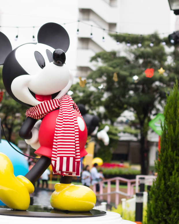 A Mickey Mouse statue dressed up in a scarf at a Christmastime celebration
