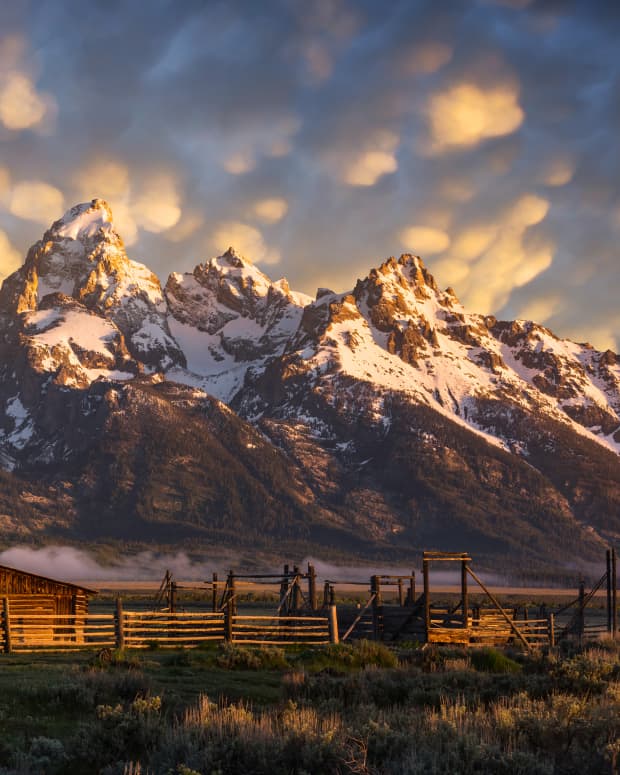 Sunset shot of the John Moulton Barn in Grand Teton National Park, with the mountains filling the scenery behind it