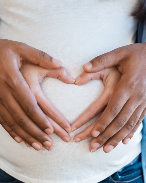 pregnant woman making heart hands on belly