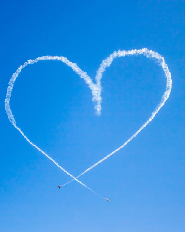 A heart made from the vapor trails of two airplanes in a bright blue sky