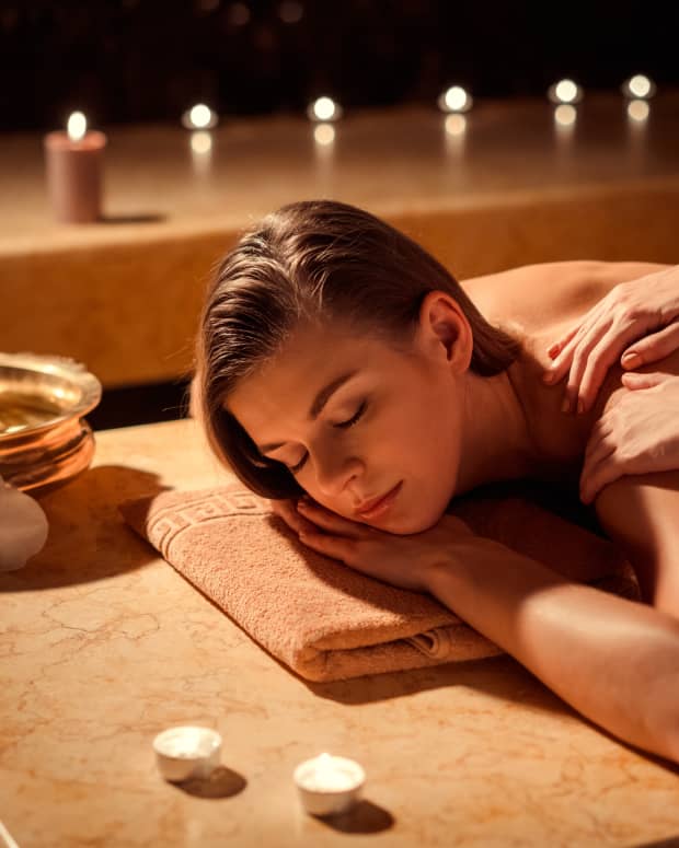 Young woman getting a back massage in a candlelit spa setting