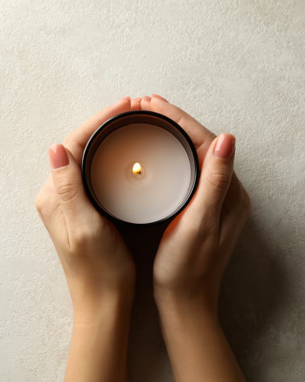 Female hands wrapped around a lit candle