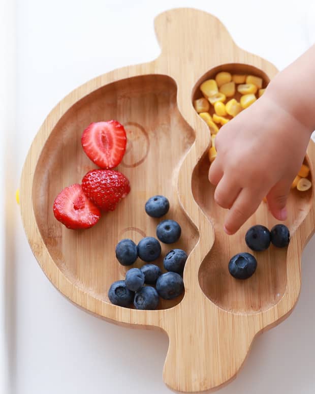toddler with plate of fruit