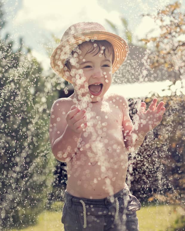 little boy playing in the sprinkler