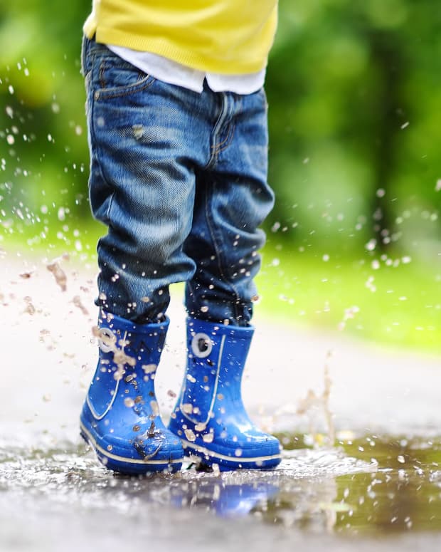 kid jumping in puddle in rain boots