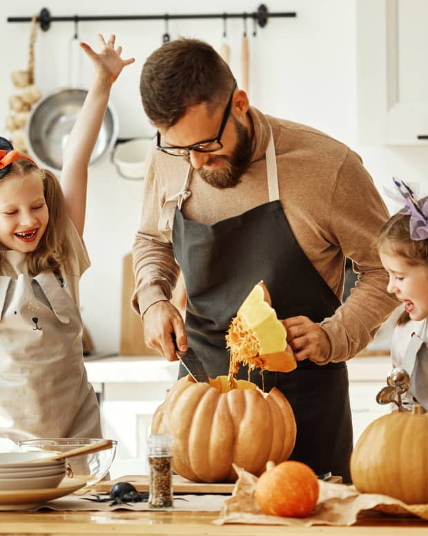 dad carving pumpkin with kids