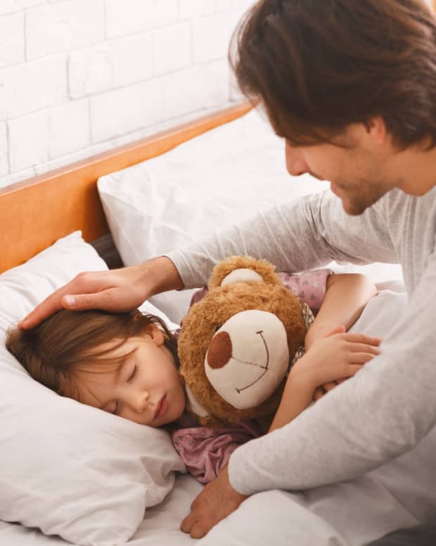 dad tucking child into bed
