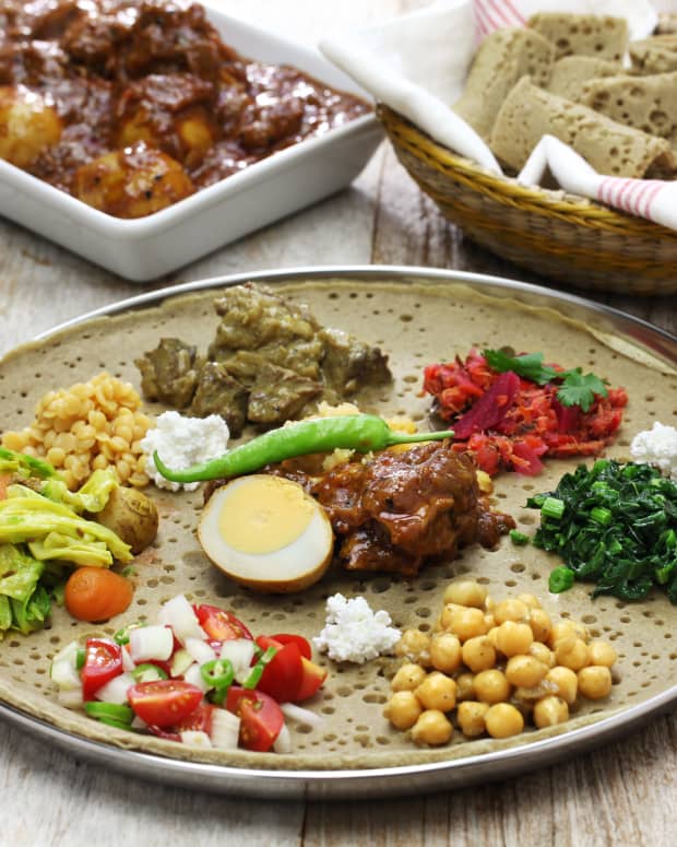Ethiopian food, including injera loaded with stews, vegetables, salads, and a hard boiled egg and chili