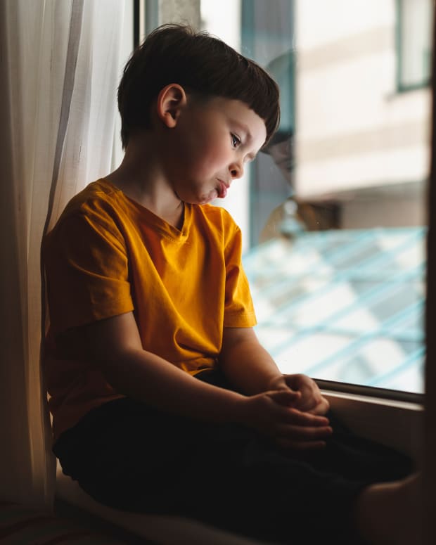 little boy sitting by window