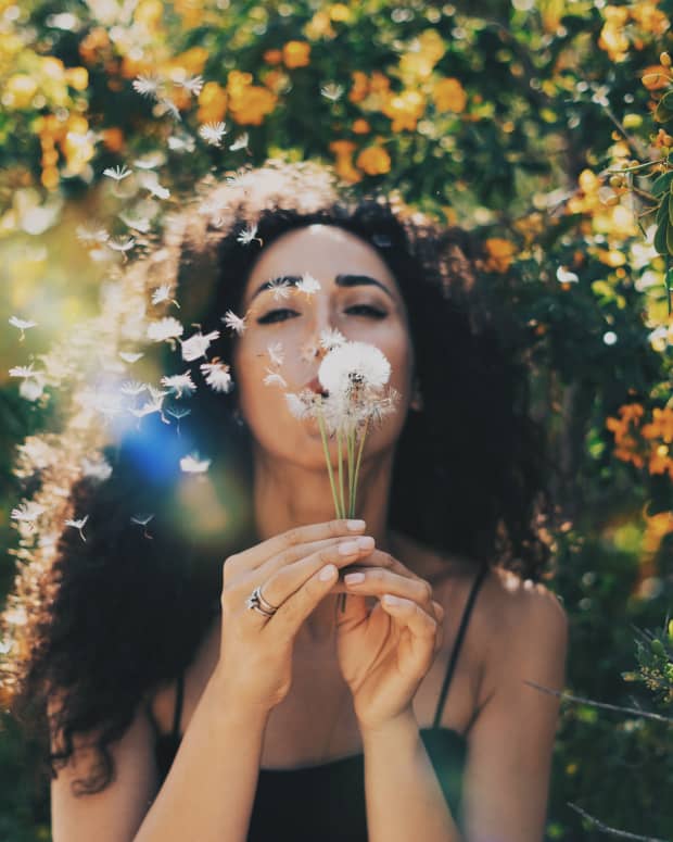 woman blowing dandelion