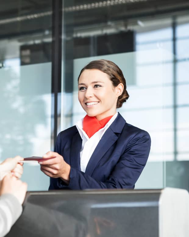 Smiling gate agent taking a woman's boarding pass