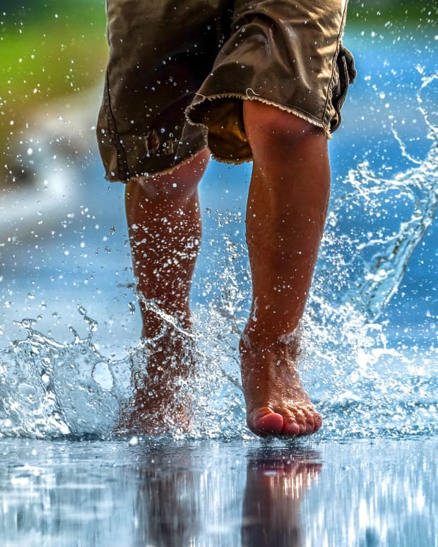 child splashing in a puddle