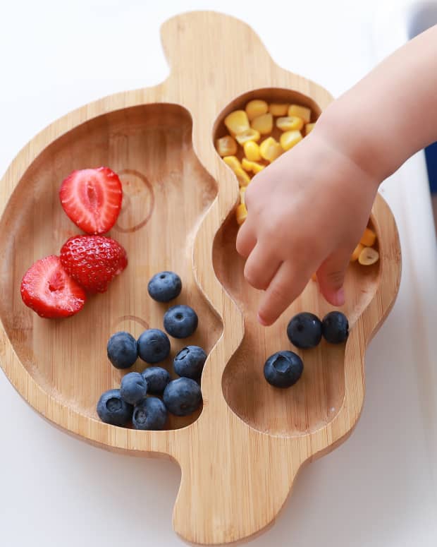 toddler eating fruit on a plate