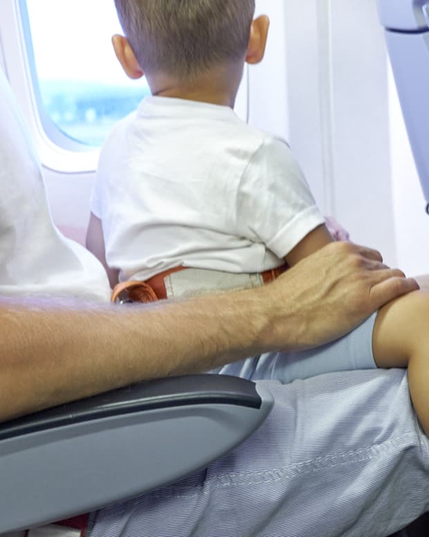 little boy sitting on parent's lap on plane