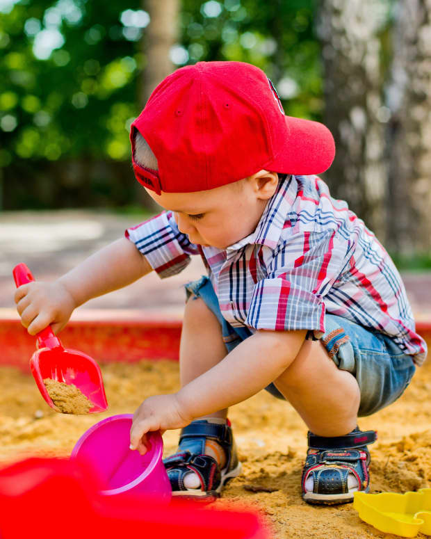 toddler boy playing in sandbox