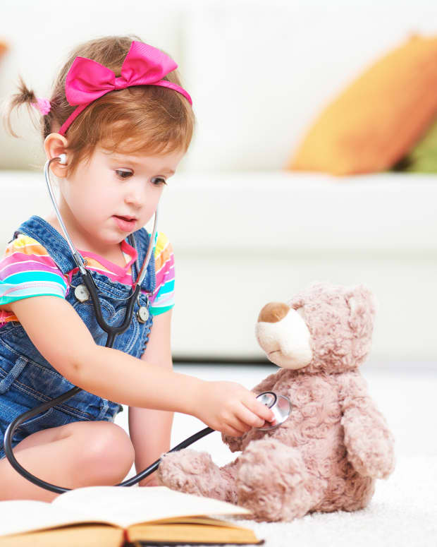 toddler little girl playing doctor with stuffed bear