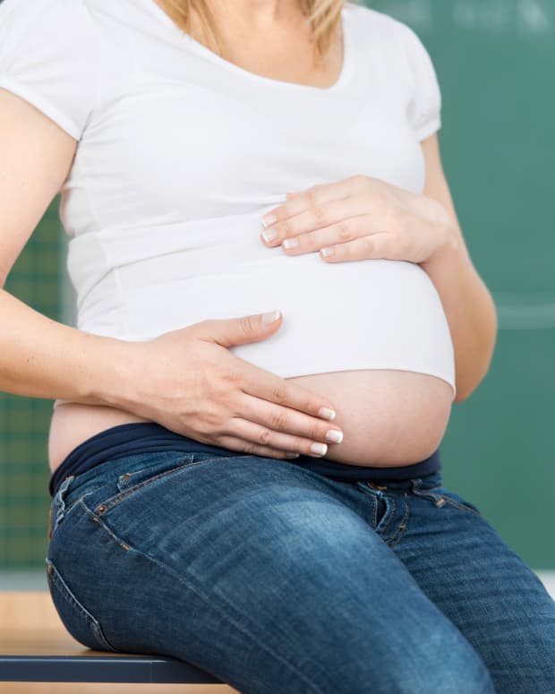 pregnant teacher sitting on desk